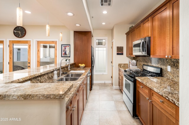 kitchen with sink, light stone counters, hanging light fixtures, stainless steel appliances, and decorative backsplash