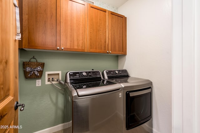 clothes washing area with cabinets and washing machine and clothes dryer