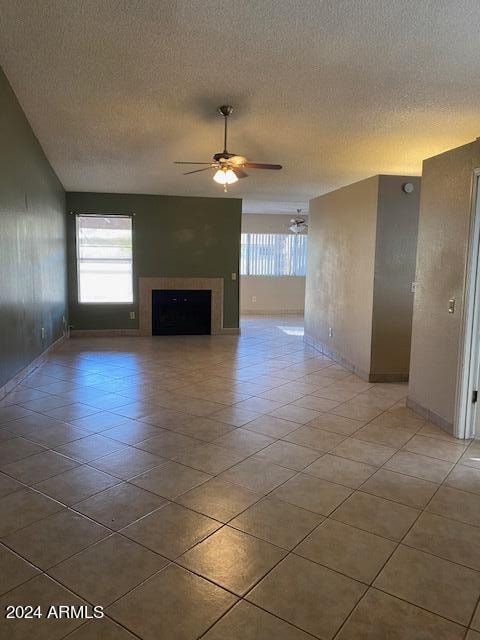 unfurnished living room featuring ceiling fan, light tile patterned flooring, and a textured ceiling