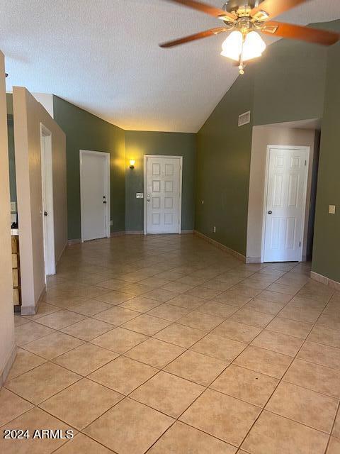 tiled empty room featuring ceiling fan, a textured ceiling, and high vaulted ceiling