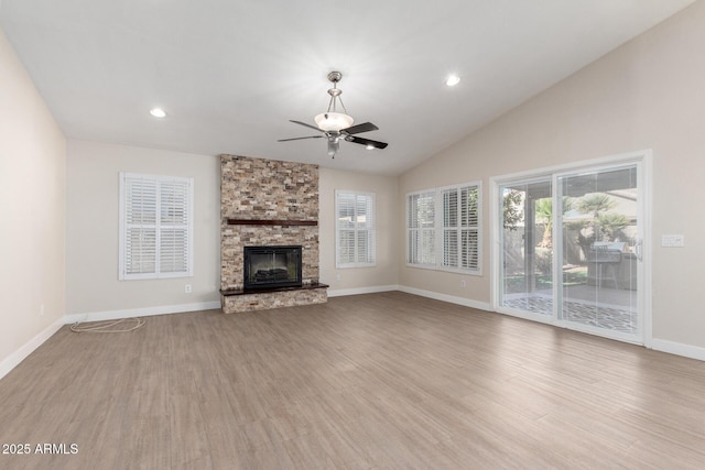 unfurnished living room featuring ceiling fan, vaulted ceiling, a fireplace, and light hardwood / wood-style flooring