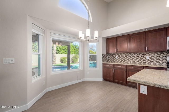 kitchen with pendant lighting, an inviting chandelier, a healthy amount of sunlight, and tasteful backsplash