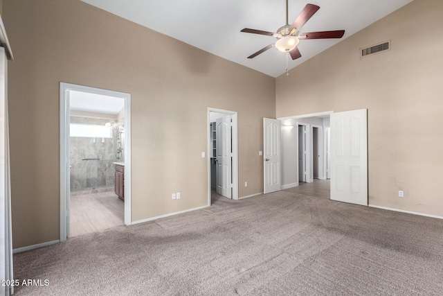 unfurnished bedroom featuring ensuite bathroom, ceiling fan, light carpet, and high vaulted ceiling