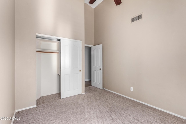 unfurnished bedroom featuring carpet flooring, ceiling fan, a high ceiling, and a closet