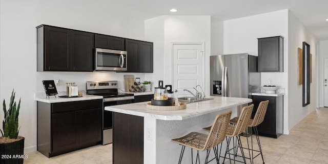 5549 E Mearn Rd, San Tan Valley, AZ 85140 - kitchen featuring stainless steel appliances, a sink, a breakfast bar, a kitchen island with sink, and dark cabinets