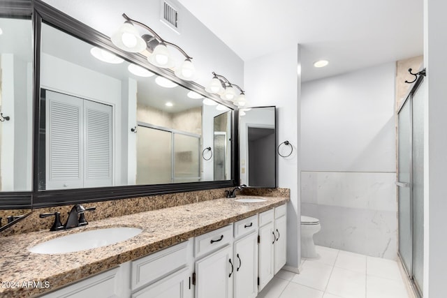 bathroom featuring toilet, vanity, tile patterned floors, and an enclosed shower