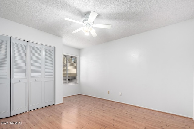 unfurnished bedroom featuring a closet, a textured ceiling, light hardwood / wood-style floors, and ceiling fan