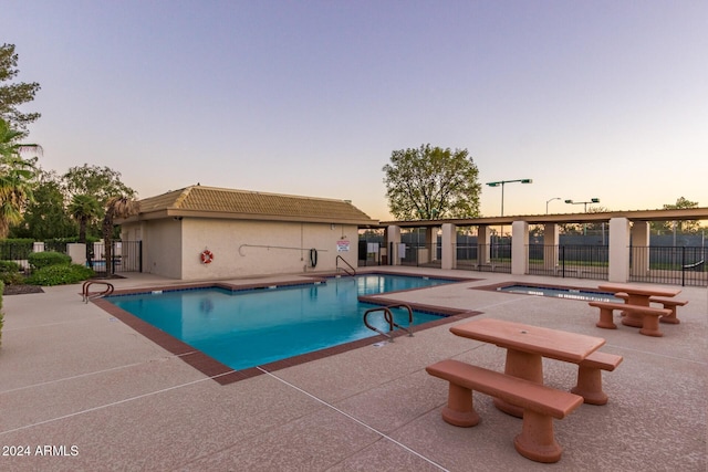 pool at dusk featuring a patio