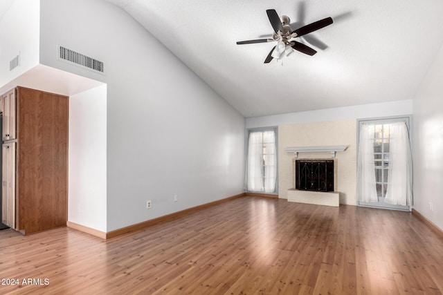 unfurnished living room featuring hardwood / wood-style flooring, ceiling fan, lofted ceiling, and a brick fireplace