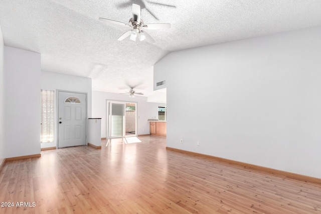 unfurnished living room featuring ceiling fan, light hardwood / wood-style floors, a textured ceiling, and vaulted ceiling