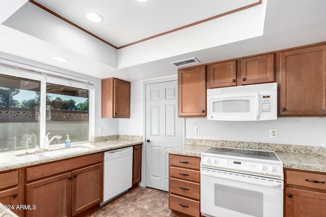 kitchen featuring light stone countertops, white appliances, a tray ceiling, and sink