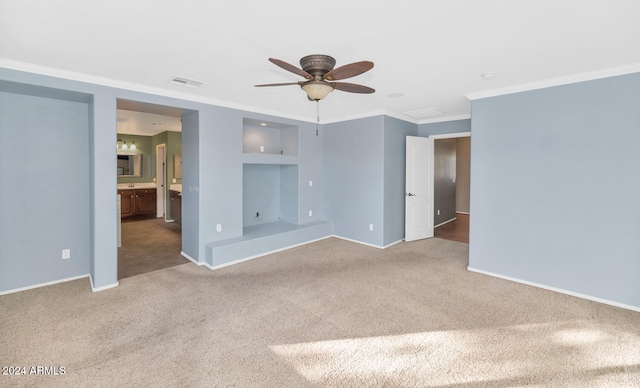 carpeted spare room featuring built in shelves, ceiling fan, and ornamental molding