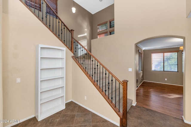 stairway with hardwood / wood-style floors, a towering ceiling, and crown molding