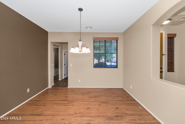 unfurnished dining area featuring hardwood / wood-style flooring and a notable chandelier