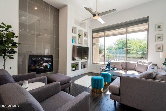 living area with a ceiling fan, built in features, baseboards, and wood finished floors