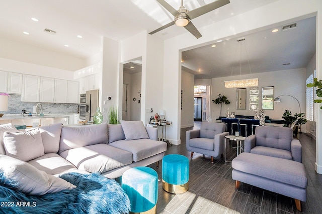 living room with dark wood-style flooring, visible vents, recessed lighting, and ceiling fan with notable chandelier