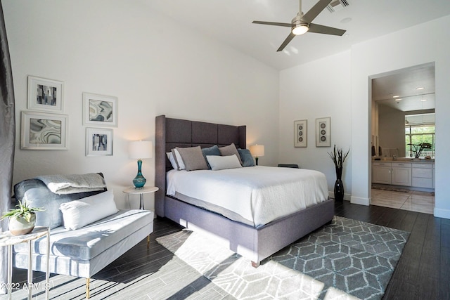bedroom featuring lofted ceiling, baseboards, ensuite bath, visible vents, and wood finished floors