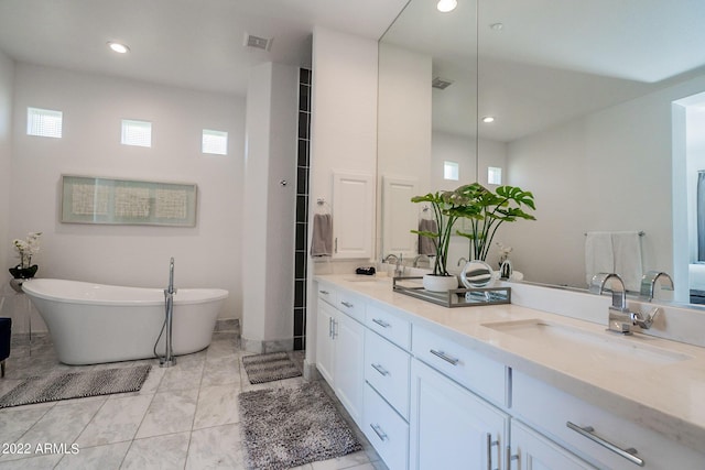 full bath featuring visible vents, a sink, double vanity, and a freestanding bath