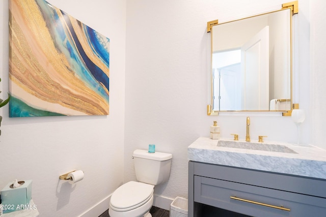 half bath featuring baseboards, toilet, and vanity