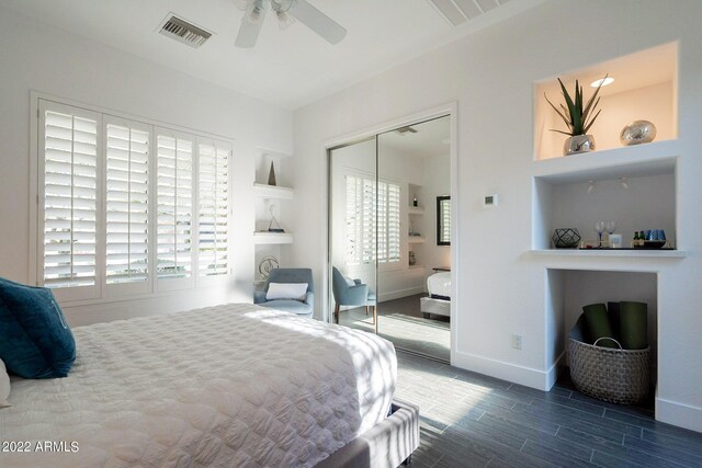 bedroom featuring wood tiled floor, multiple windows, visible vents, and a closet