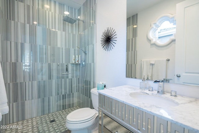 full bath featuring toilet, tiled shower, and vanity