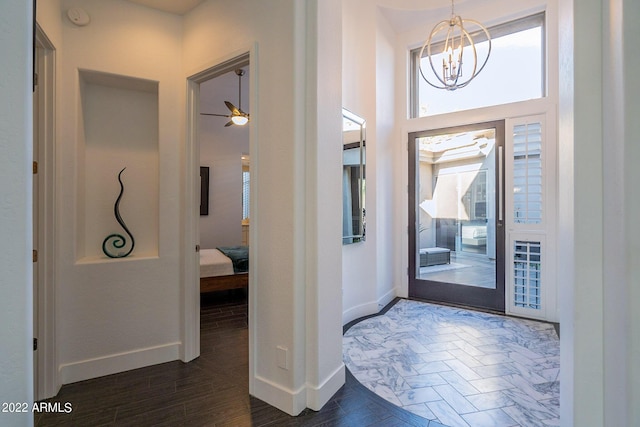 entrance foyer with dark wood-type flooring, a high ceiling, baseboards, and ceiling fan with notable chandelier