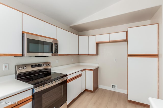 15087 N 86th Dr, Peoria, AZ 85381 - kitchen with light countertops, light wood-style flooring, stainless steel appliances, lofted ceiling, and white cabinetry