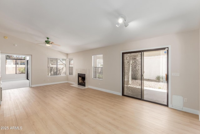 15087 N 86th Dr, Peoria, AZ 85381 - unfurnished living room with a tiled fireplace, light wood-style floors, vaulted ceiling, and ceiling fan