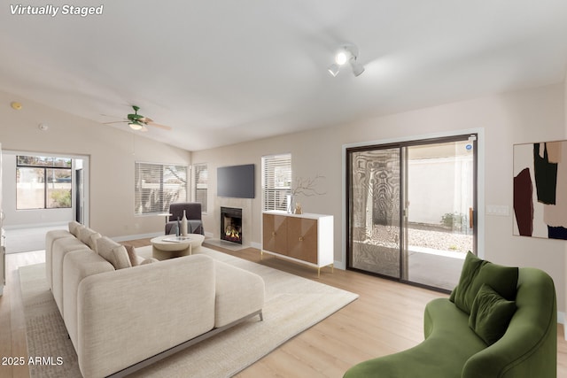 15087 N 86th Dr, Peoria, AZ 85381 - living area featuring a ceiling fan, a fireplace with flush hearth, lofted ceiling, light wood-style flooring, and baseboards