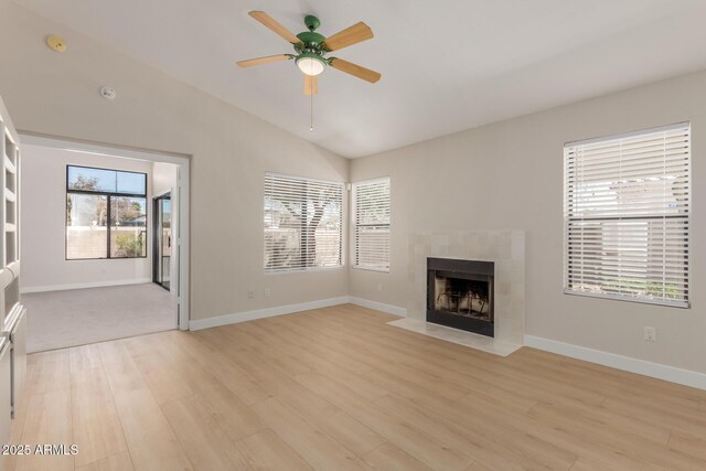 15087 N 86th Dr, Peoria, AZ 85381 - unfurnished living room with light wood-style flooring, baseboards, ceiling fan, a tiled fireplace, and lofted ceiling