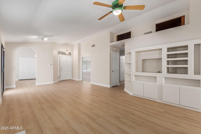 15087 N 86th Dr, Peoria, AZ 85381 - unfurnished living room with arched walkways, baseboards, ceiling fan, and light wood-style flooring