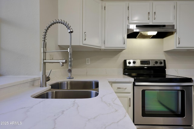 kitchen with light stone counters, white cabinets, sink, and electric range