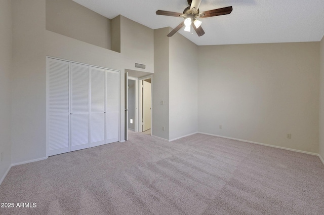 unfurnished bedroom with ceiling fan, light colored carpet, high vaulted ceiling, and a closet