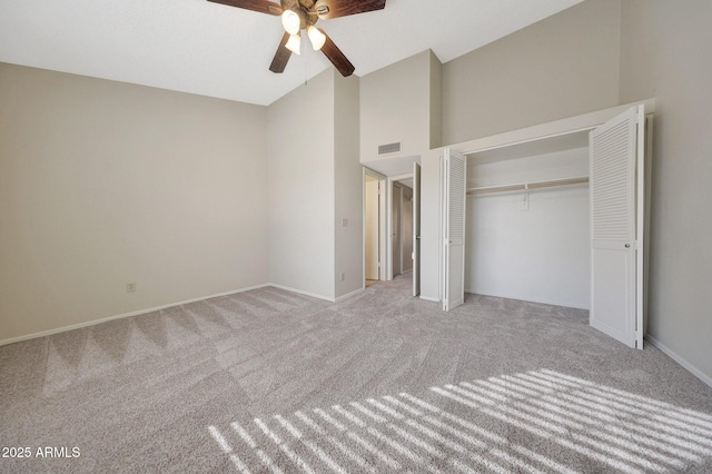 unfurnished bedroom with ceiling fan, light colored carpet, high vaulted ceiling, and a closet