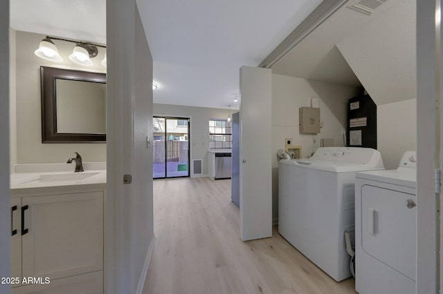 laundry area featuring sink, washer and clothes dryer, and light hardwood / wood-style floors