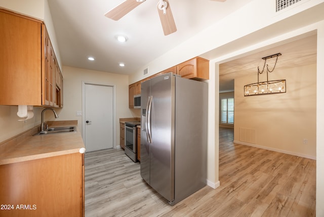 kitchen with ceiling fan with notable chandelier, stainless steel appliances, light hardwood / wood-style floors, sink, and pendant lighting