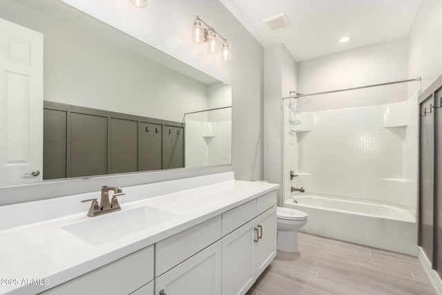 full bathroom featuring vanity, hardwood / wood-style floors, tiled shower / bath combo, and toilet