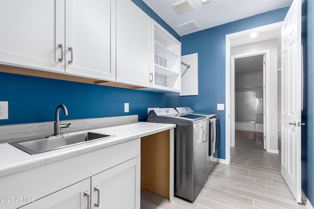 laundry area featuring light hardwood / wood-style floors, cabinets, washer and clothes dryer, and sink