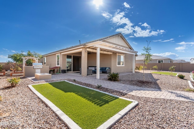 rear view of property featuring area for grilling, a pergola, and a patio area