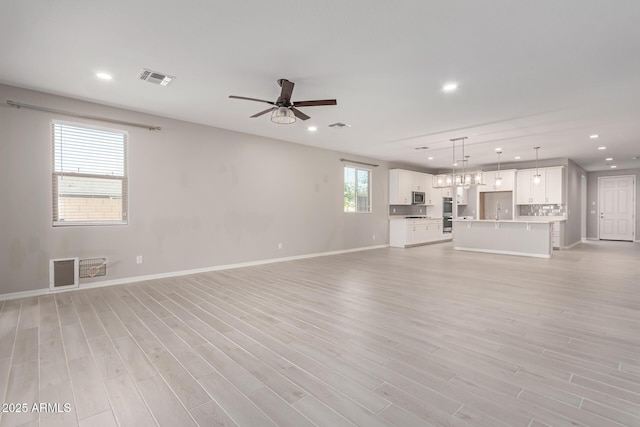 unfurnished living room featuring ceiling fan and light wood-type flooring