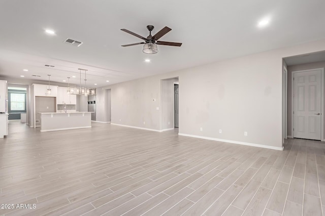 unfurnished living room featuring light wood-type flooring and ceiling fan