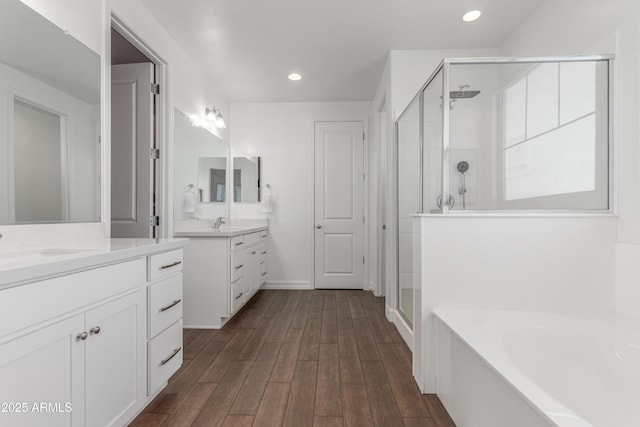 23042 E Excelsior Ave, Queen Creek, AZ 85142 - bathroom with a stall shower, two vanities, a bath, wood finished floors, and recessed lighting