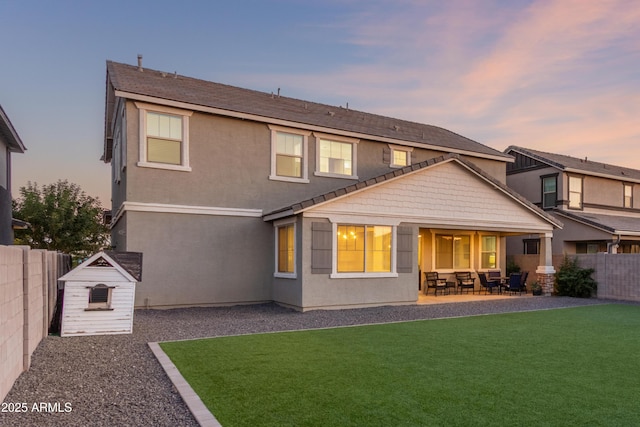 23042 E Excelsior Ave, Queen Creek, AZ 85142 - back of house at dusk featuring a fenced backyard, a patio, a storage unit, and stucco siding
