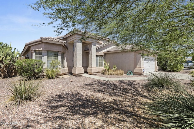 mediterranean / spanish home with a tiled roof, an attached garage, and stucco siding