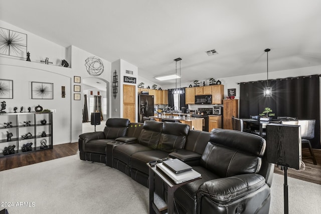 living room with visible vents, arched walkways, dark wood-style floors, and vaulted ceiling