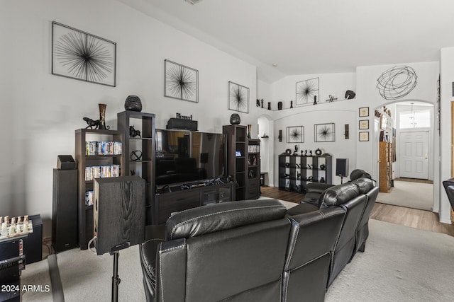 living area featuring arched walkways, lofted ceiling, and wood finished floors