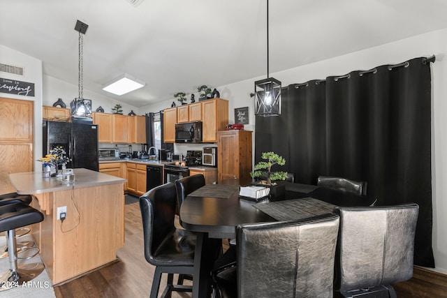 kitchen with a kitchen island, vaulted ceiling, dark hardwood / wood-style flooring, pendant lighting, and black appliances