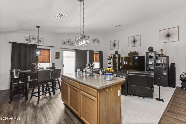 kitchen with visible vents, pendant lighting, wood finished floors, a center island, and light countertops