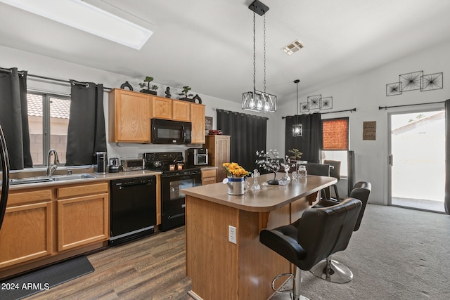 kitchen with black appliances, vaulted ceiling, a healthy amount of sunlight, and a kitchen island