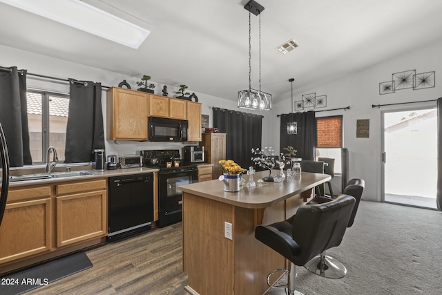 kitchen featuring a center island, vaulted ceiling, a kitchen breakfast bar, black appliances, and a sink